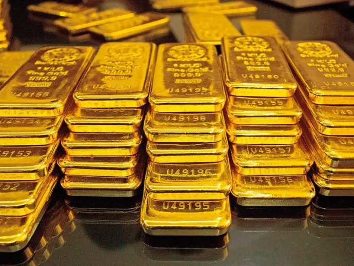 Stacks of shiny gold bars arranged on a reflective black surface.
